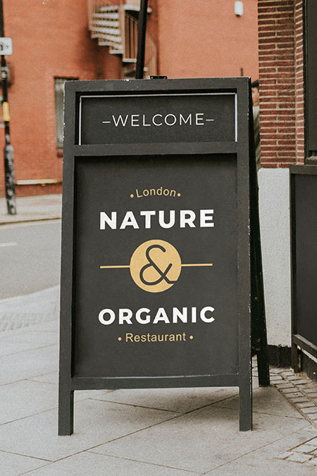 A-frame sidewalk sign on outdoor pavement near storefront entrance, used for daily promotions and notices