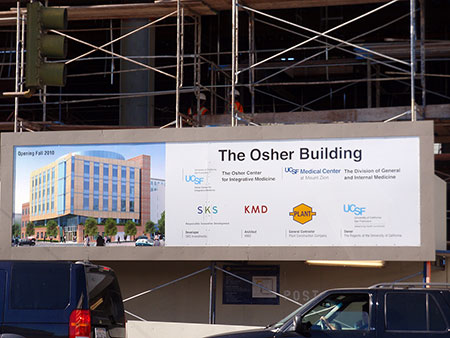 Construction banners displayed on a jobsite fence, combining safety notices with bold branded graphics for public awareness.