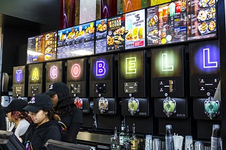 Digital menu boards display menu items, prices, and promotions in a sleek, modern quick-service restaurant setting.