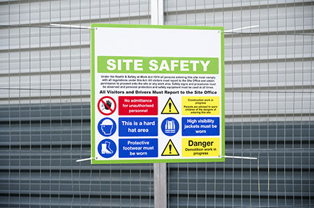 Order OSHA Safety Signs for Facilities - Act Today Assorted OSHA safety signs mounted on a wall, featuring caution, warning, and danger messages for common workplace hazards.