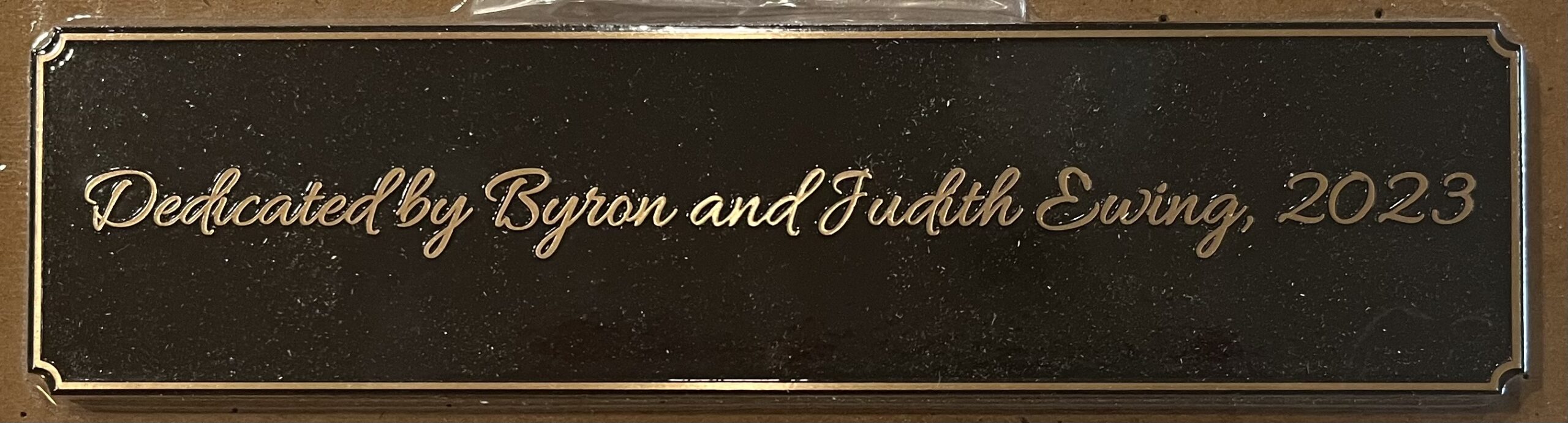 Custom metal plaque displaying professional engraved lettering for business signage, mounted on wall