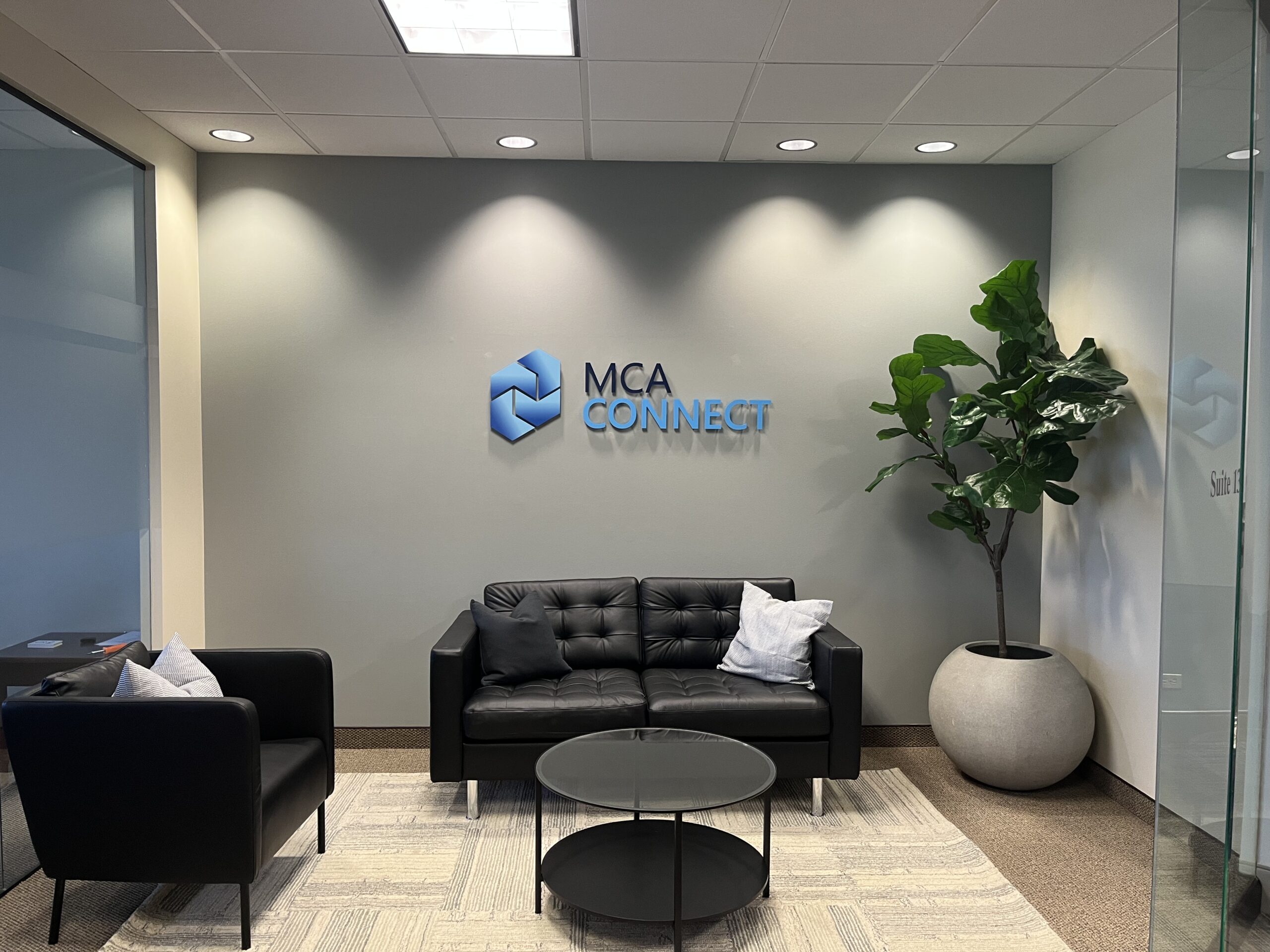 Acrylic logo sign mounted with metal stand-off studs, enhancing a modern lobby wall with crisp, professional branding.